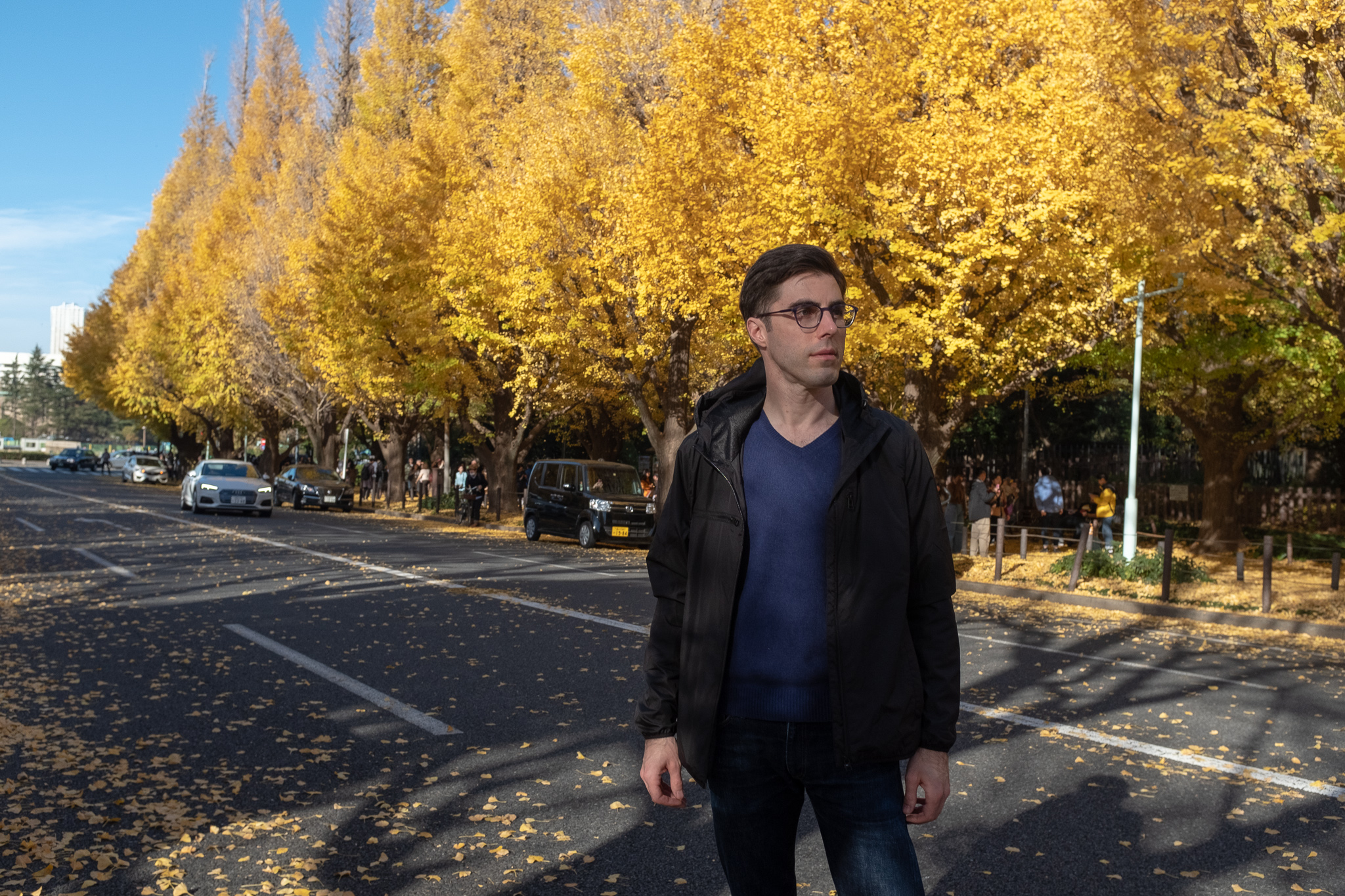 Josh wearing Baubax jacket with bright yellow leaves on trees in the background